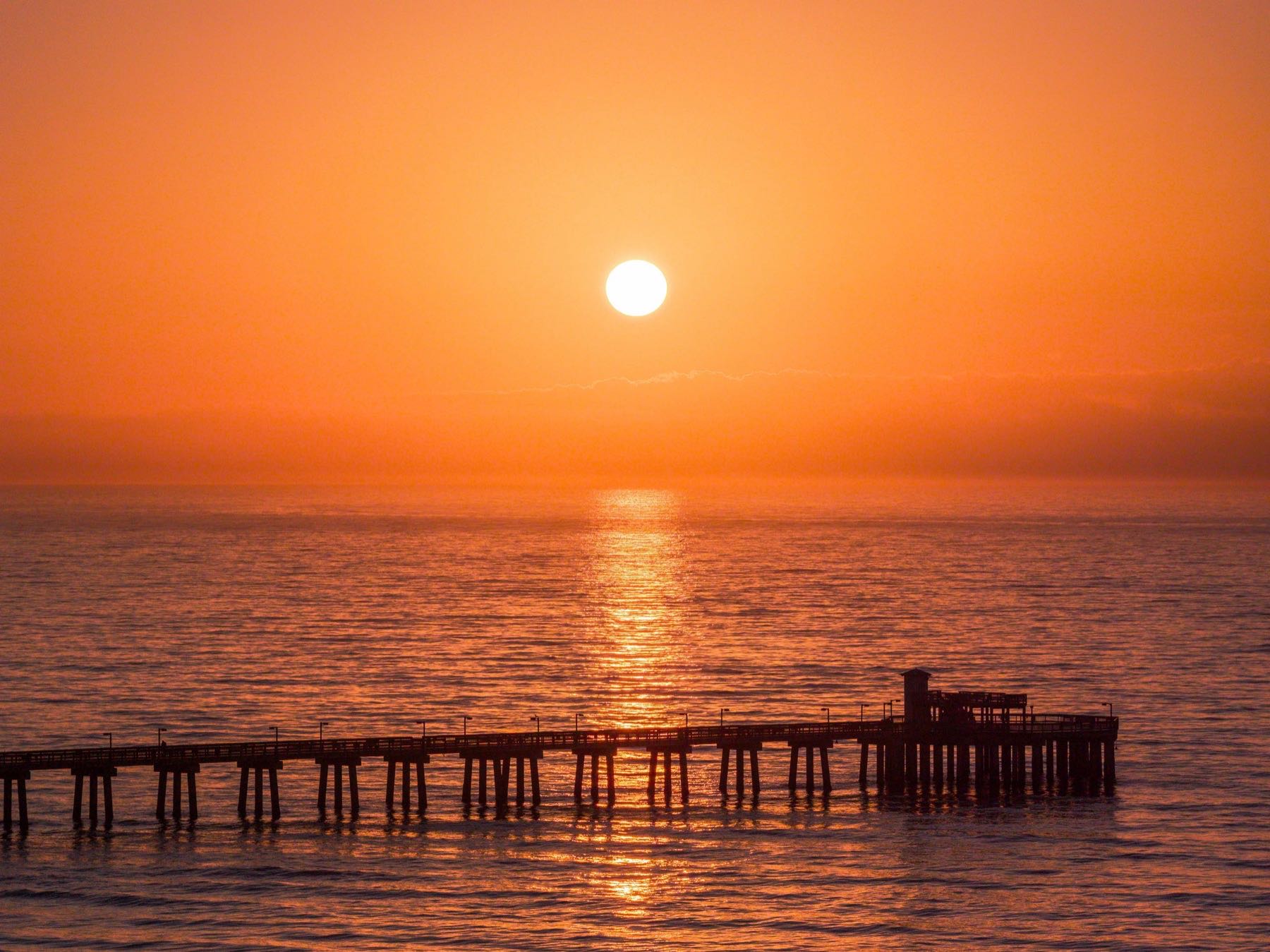 Pier silhouetted against a vivid Gulf Coast sunset