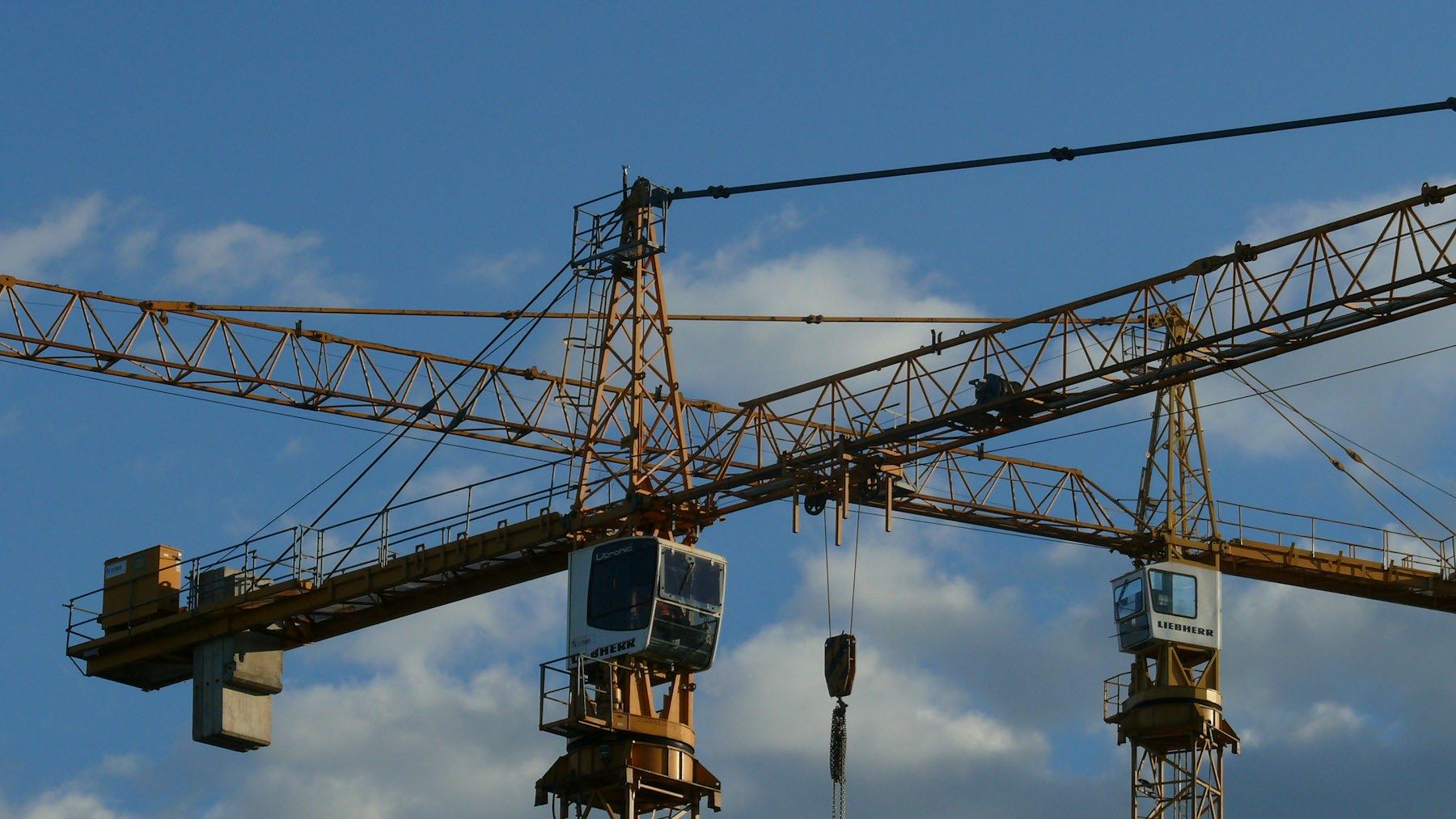 Two tower cranes against a clear blue sky at a construction site