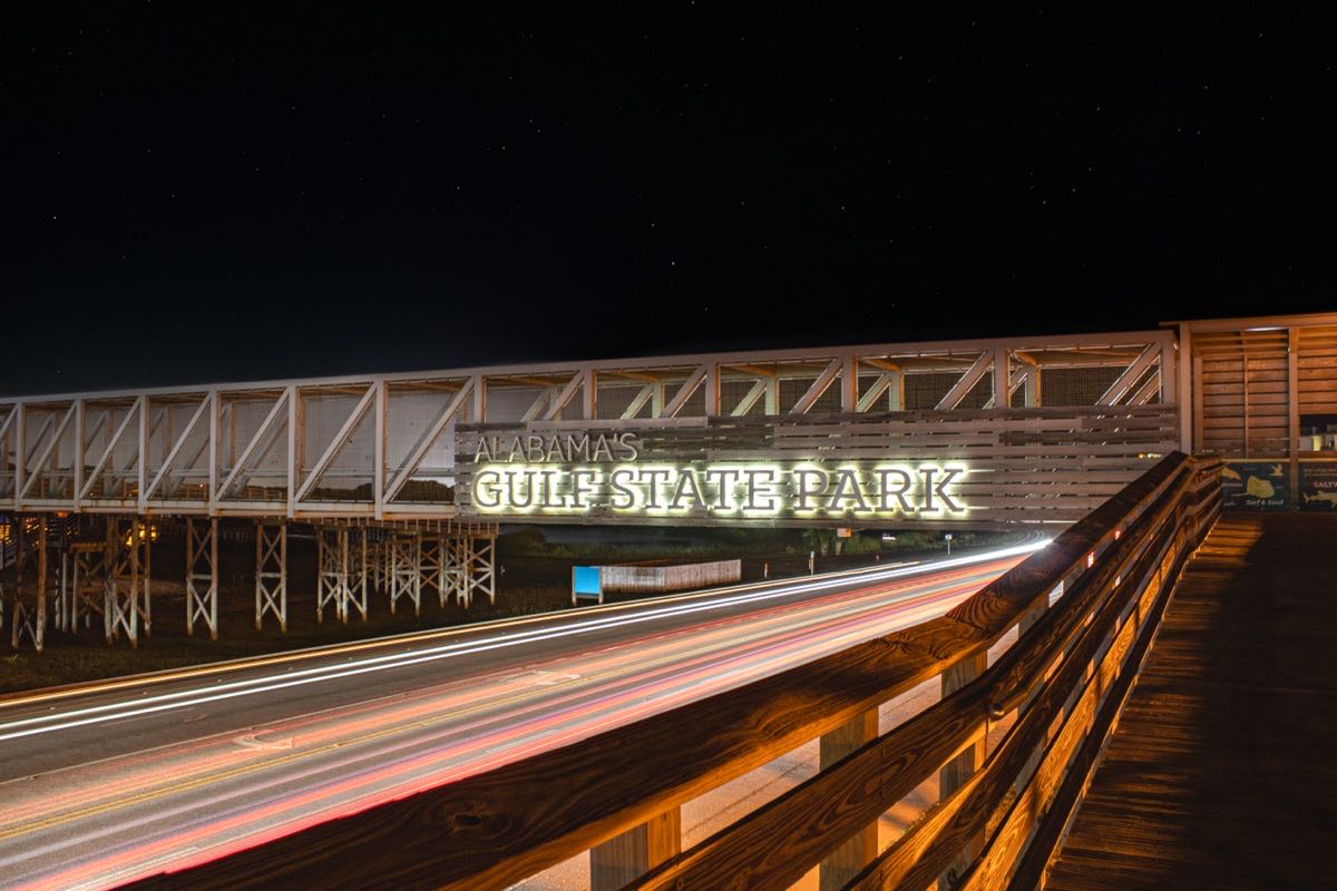 Alabama's Gulf State Park pier sign lit up at night with light trails